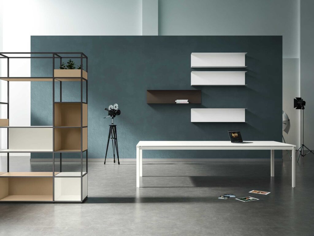 Bureau moderne et design : étagère modulaire & espace de travail Bureau moderne avec étagère modulaire noire et beige, table blanche, laptop et étagères murales sur un mur gris-bleu.