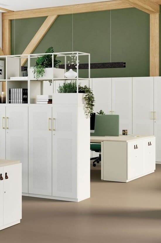Aménagement de bureau moderne avec étagères modulables blanches, plantes vertes, armoires de rangement, bureaux et chaises vertes.