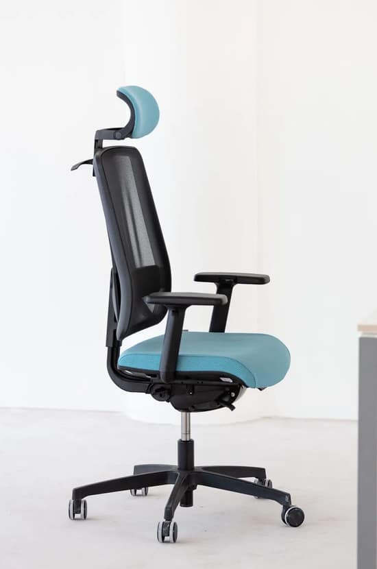 Chaise de bureau ergonomique noire et bleue avec dossier mesh, têtière et accoudoirs, sur roulettes en studio blanc.