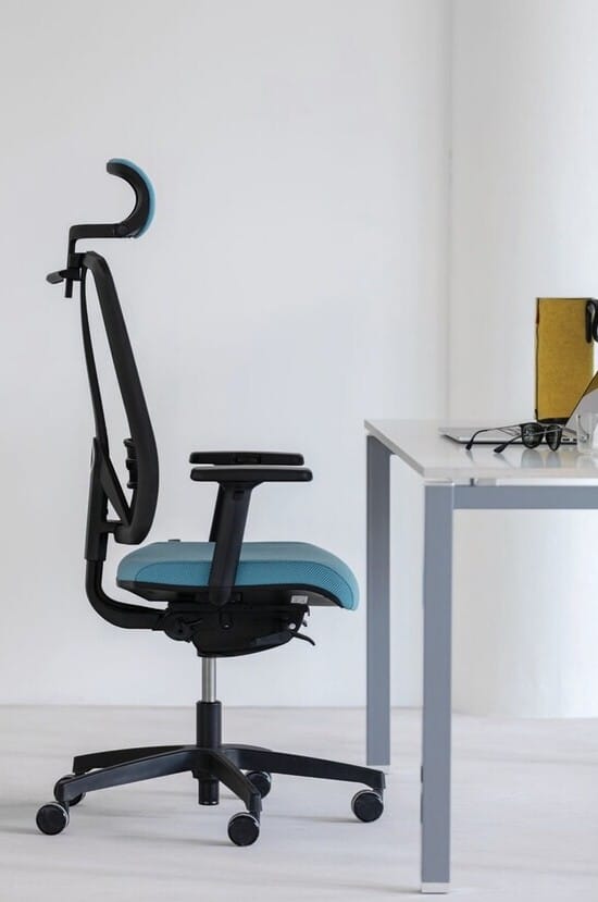 Chaise de bureau ergonomique noire avec siège bleu et appui-tête, devant un bureau blanc moderne. Idéal pour télétravail.