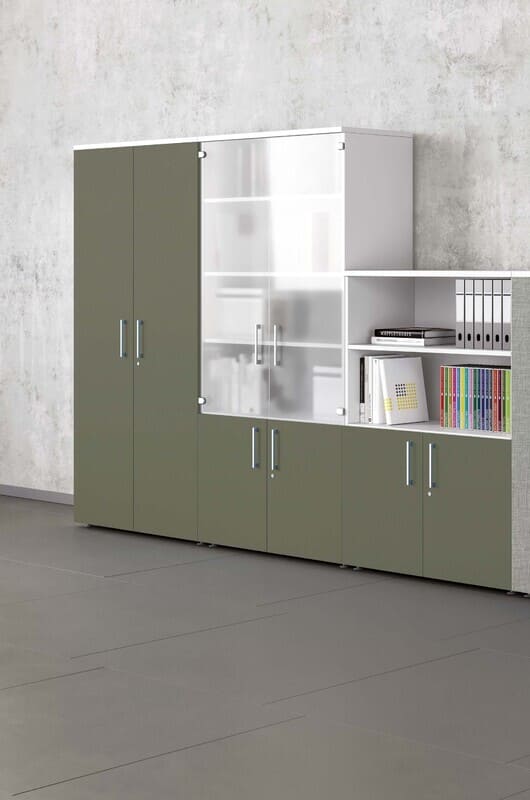 Armoire de bureau modulaire moderne vert olive et blanc. Comprend des portes pleines, des portes vitrées dépolies et des étagères ouvertes avec classeurs et livres.